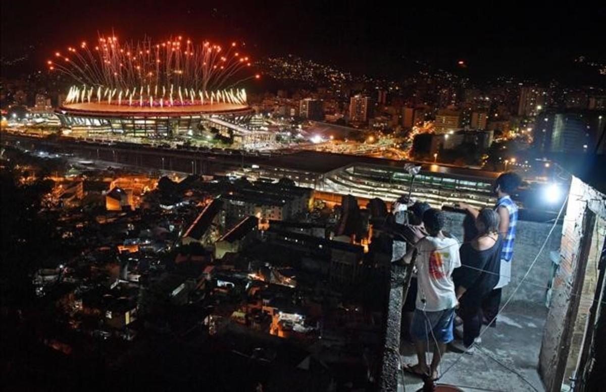 Un grupo de brasileños observan los fuegos artificiales del estadio de Maracaná, durante la ceremonia inaugural de los JJOO de Río, desde la favela Mangueira