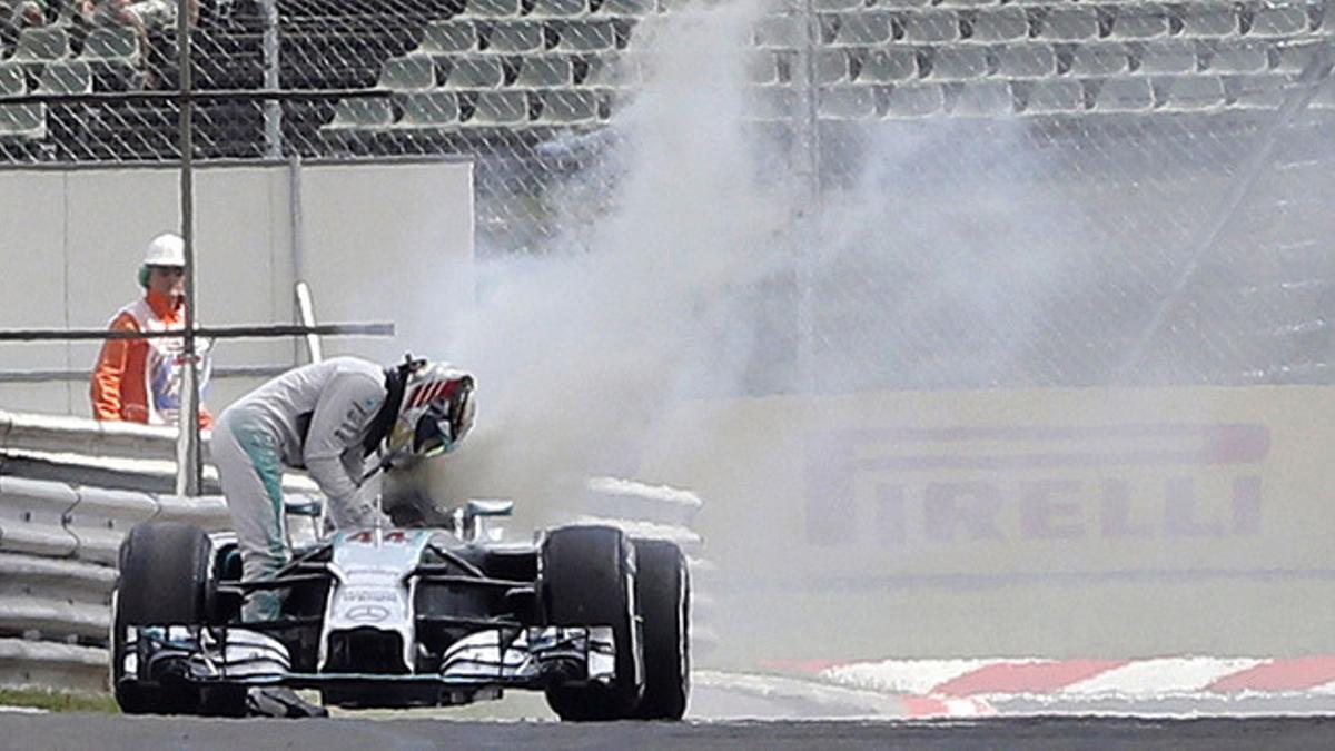 Lewis Hamilton sale de su monoplaza tras incendiarse la parte trasera del motor