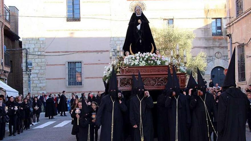 Asociadas y cofrades acompañan a la Virgen de la Soledad en la procesión de Semana Santa.