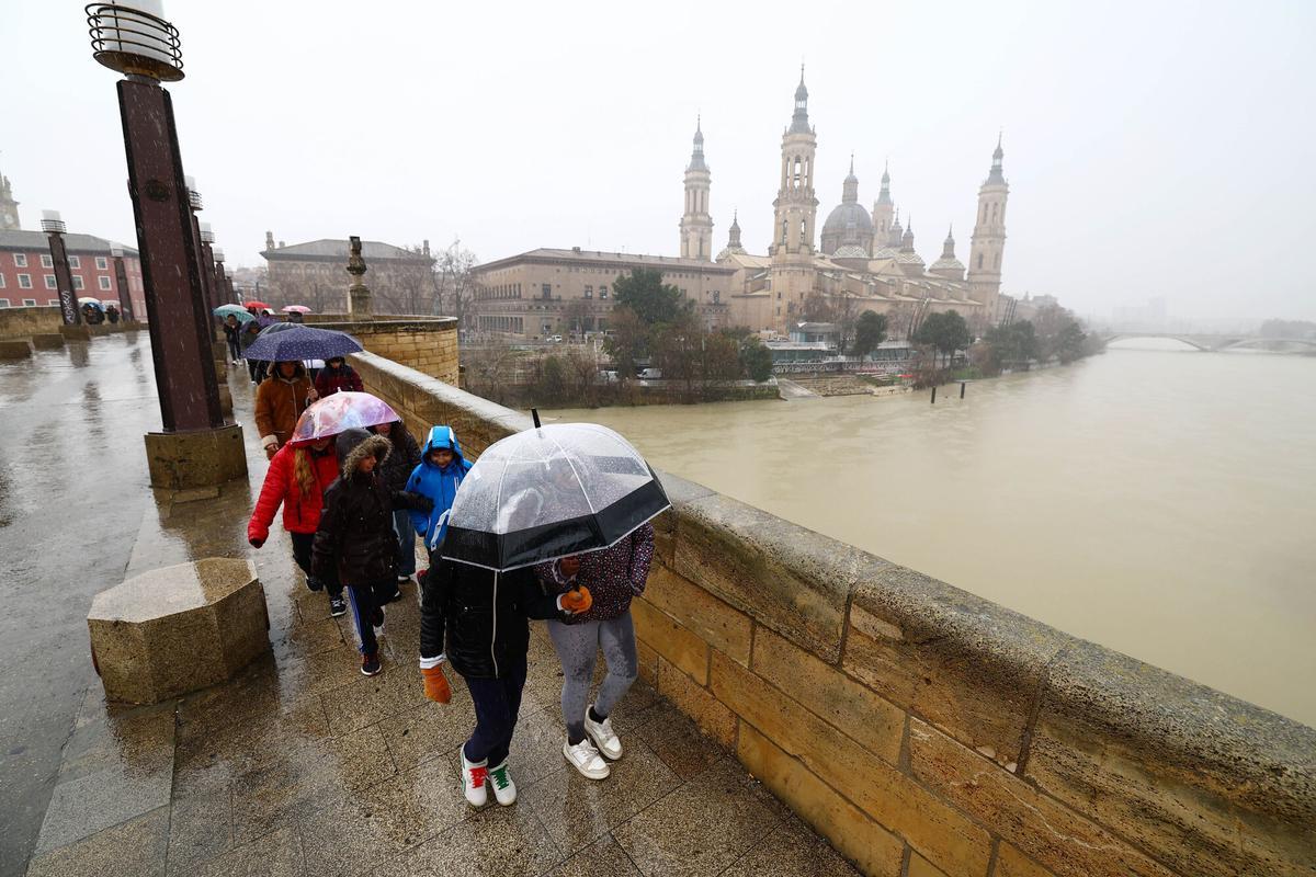 Varias personas se protegen de la lluvia con paraguas en Zaragoza