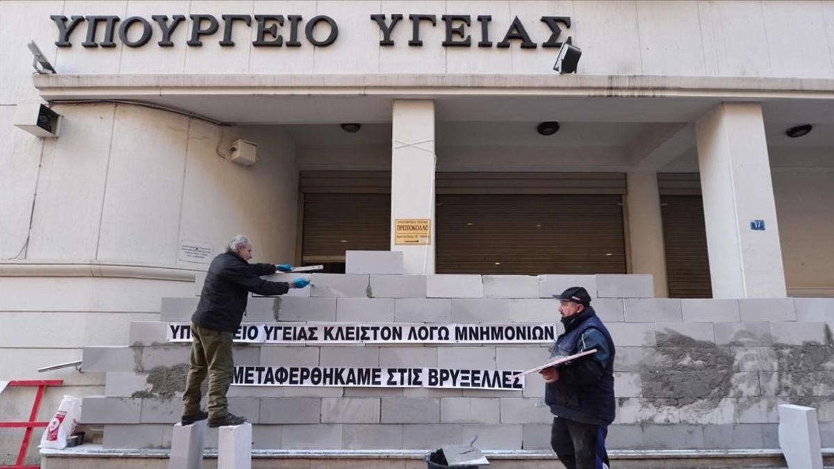 Manifestantes levantan un muro en la sede del Ministerio de Sanidad de Grecia con la inscripción 'Cerrado por el rescate. Hemos sido trasladados a Bruselas', en una protesta contra la austeridad en Atenas, en diciembre del 2016
