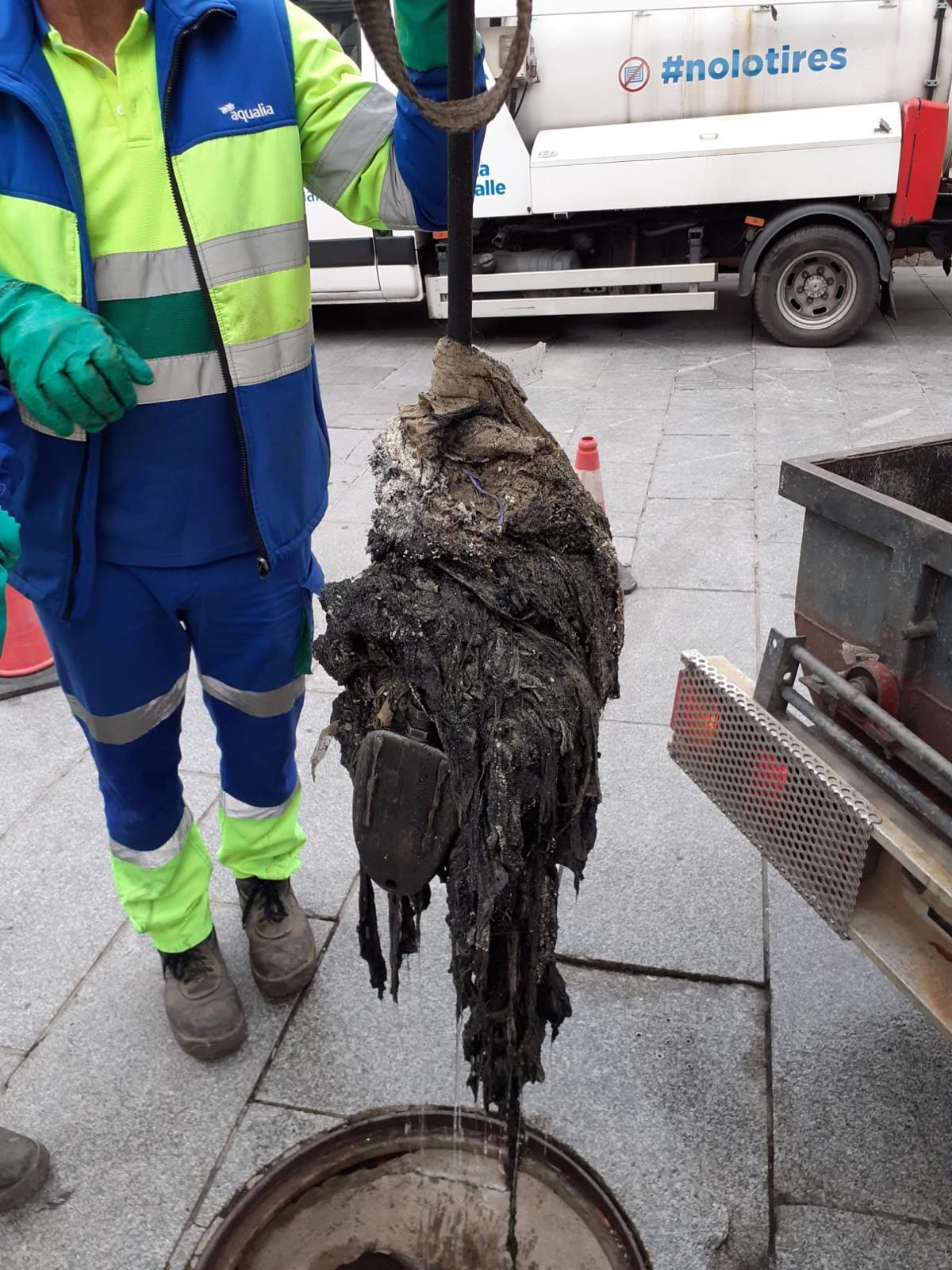 Operario de Aqualia extrayendo residuos de la red de saneamiento