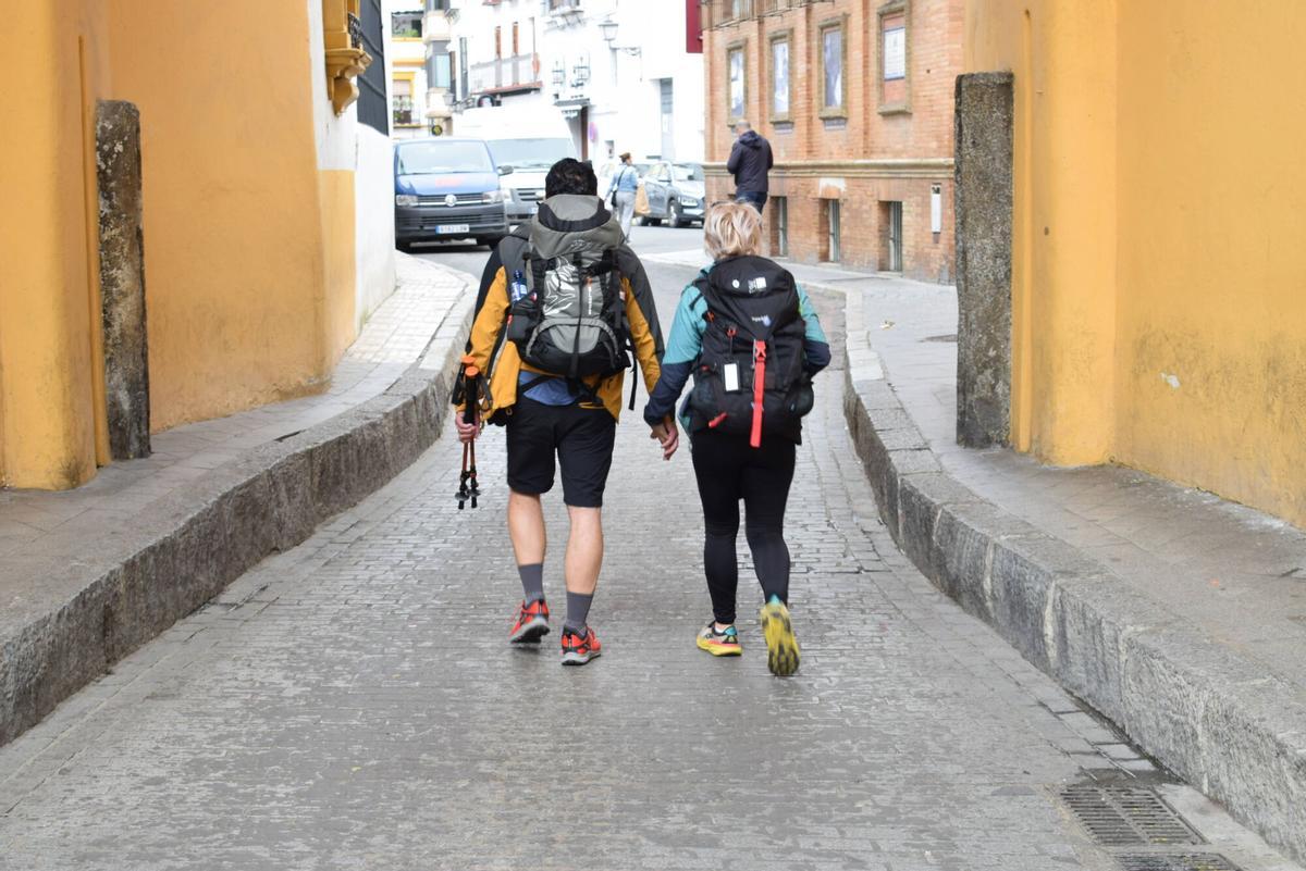 Una pareja de turistas muy bien equipados pasean por una calle de Sevilla