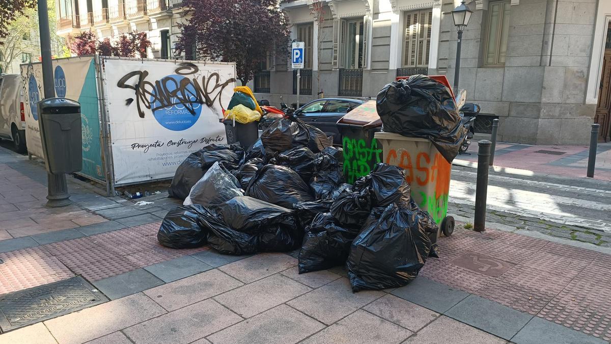 Cubos desbordados de bolsas en una céntrica calle próxima a Cibeles.