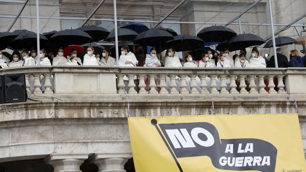 La corte de las falleras en el balcón del ayuntamiento este año protegidas con pañolones y paraguas