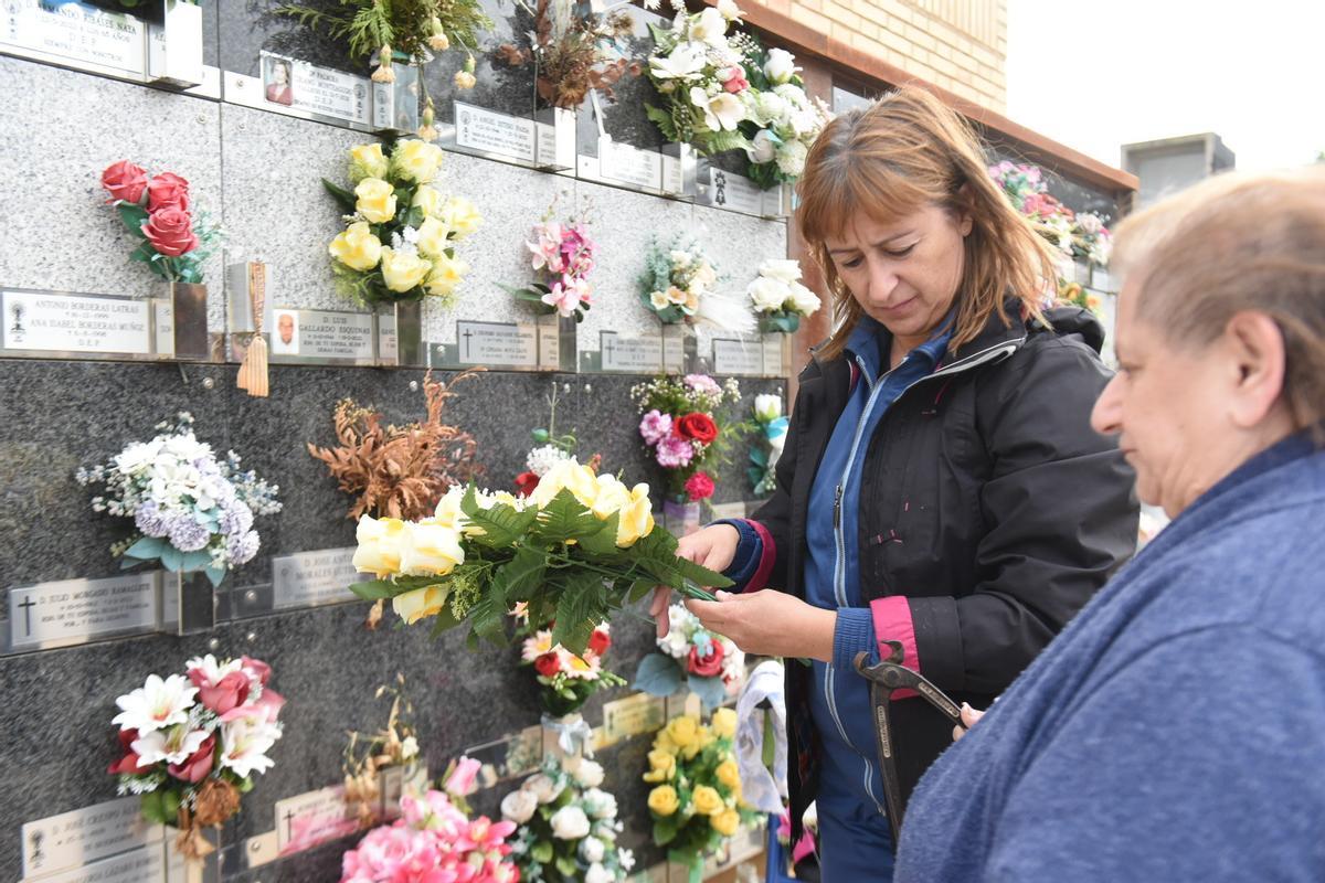 Dos mujeres colocan las flores en la tumba de un familiar querido, este sábado.