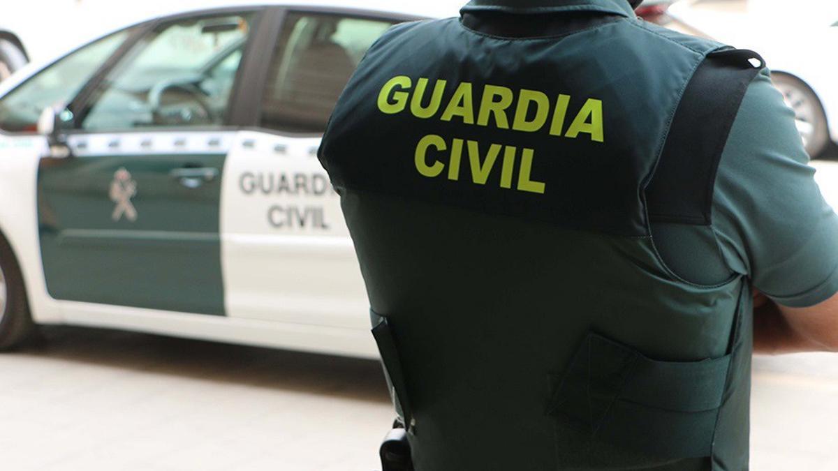 Un guardia civil junto a su coche patrulla.