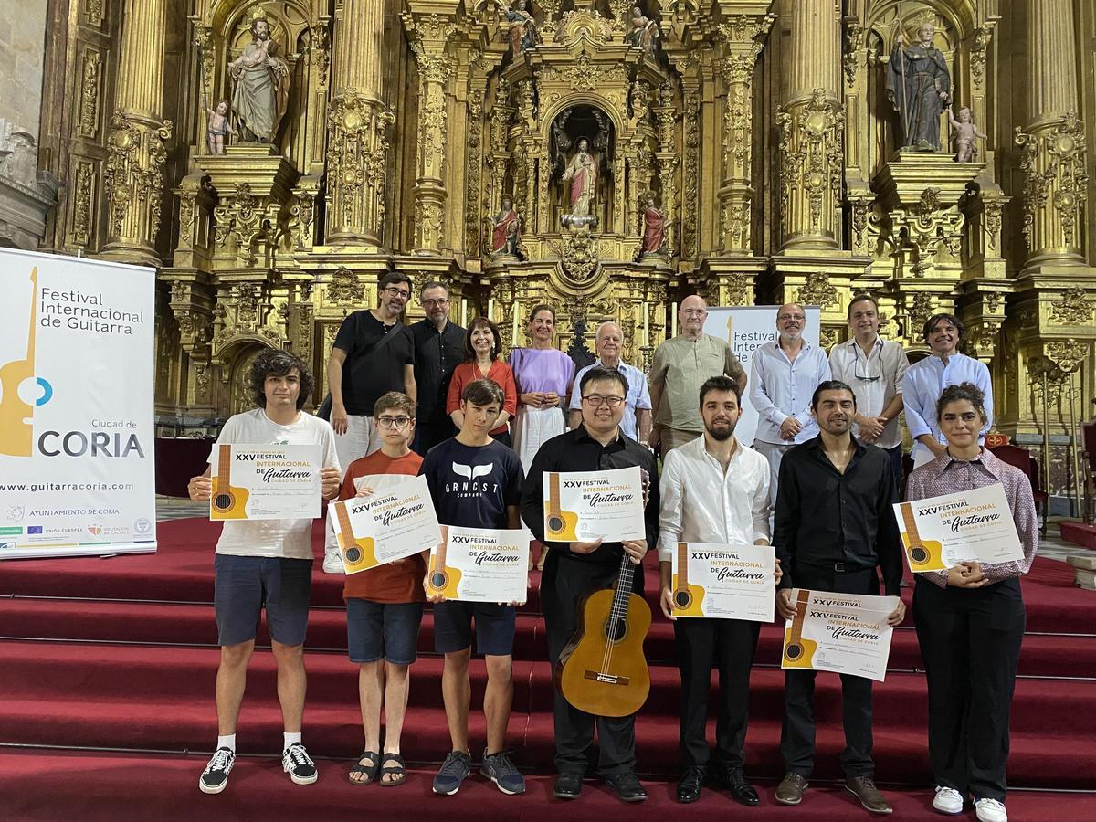 El ganador, en el centro con la guitarra, entre otros premiados y detrás organizadores y autoridades locales.