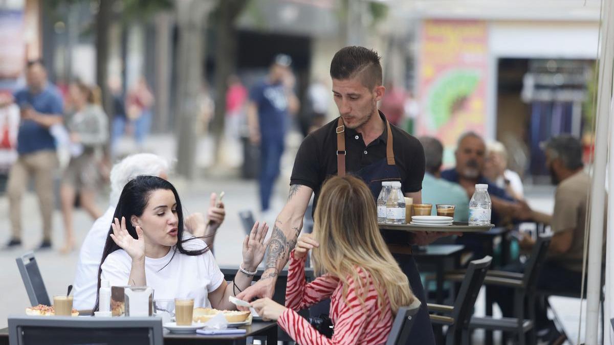Un camarero atiende a unas clientas.