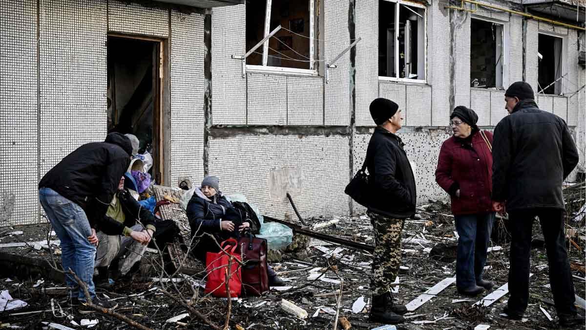 Gente en el exterior de un edificio destruido tras bombardeos en la ciudad de Chugulv, en Ucrania.