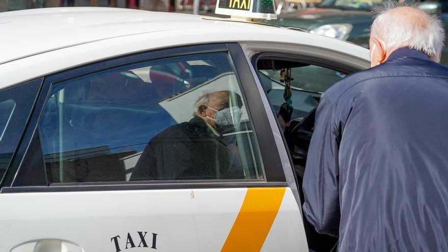 Una persona mayor con mascarillas coge un taxi, archivo