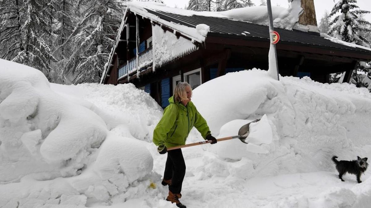 Una mujer limpia la nieve de los accesos a su casa en Val d'Isere, en los Alpes franceses.