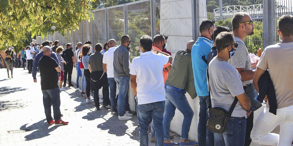 Familiares y aficionados siguiendo un partido de categorías inferiores en la Ciudad Deportiva desde la valla exterior del recinto.