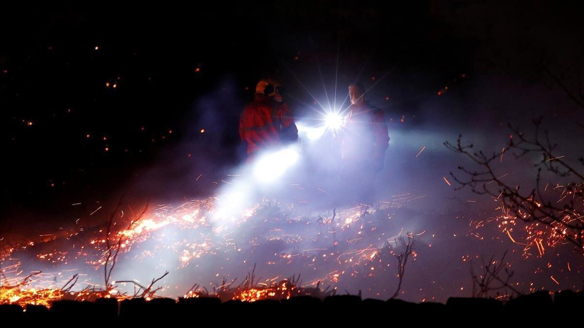 Los bomberos intentan apagar un incendio en un páramo en el pueblo de Uppermill, Gran Bretaña.