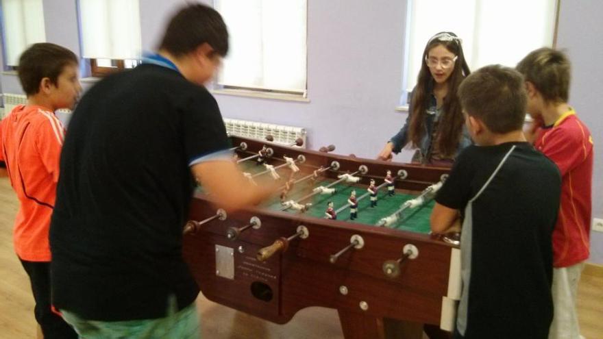 Varios niños y una niña jugando ayer por la mañana al futbolín