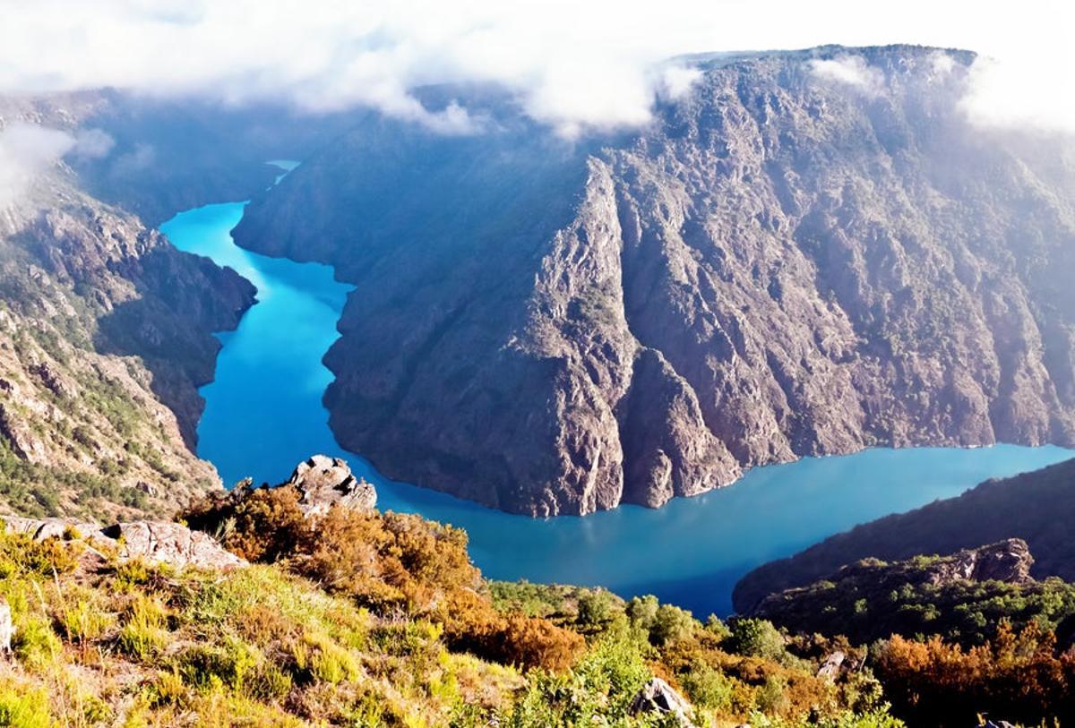 Los buenos días nos llegan hoy desde el Cañón del Sil, una garganta excavada por el río Sil. Este cañón está ubicado en la zona de la Ribeira Sacra, en Galicia y se conforma como uno de los elementos más importantes de la zona por sus sinuosas y bellas curvas. Además, es un lugar que refugia a numerosas especies animales y vegetales de la zona.