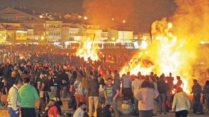 Una multitud se dio cita anoche en el arenal de Panxón alrededor de dos grandes hogueras, muchos pertrechados con bebidas para pasar la velada.  // Marta G. Brea