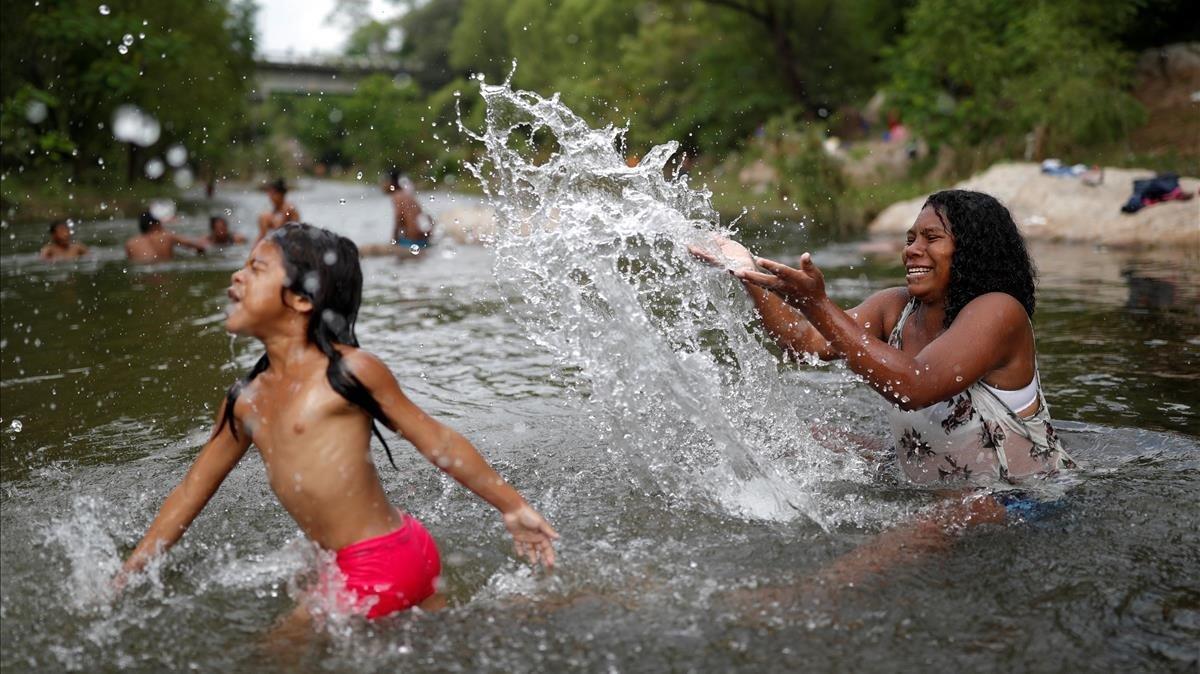 Erly Marcial hondureña de 21 años y embarazada juega con su hija Maria de 6 en el río Tapanatepec en Méjico.