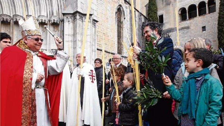 Desenes de palmes a la plaça dels Apòstols de Girona esperen la benedicció del Bisbe Francesc.