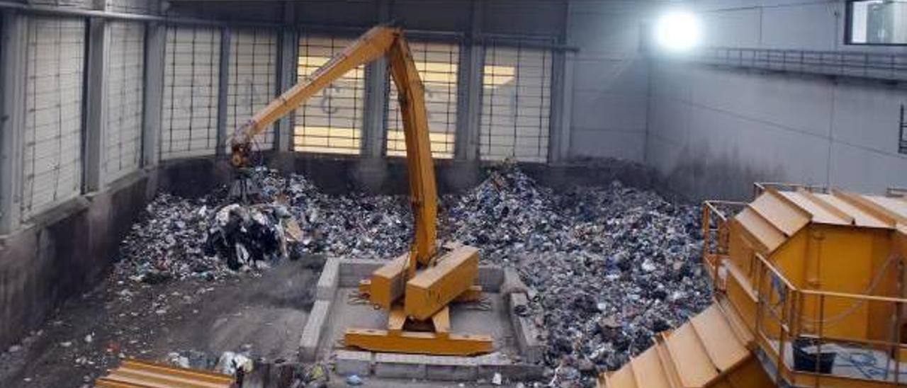 Una máquina recoge los residuos en la planta de tratamiento de Guadassuar.