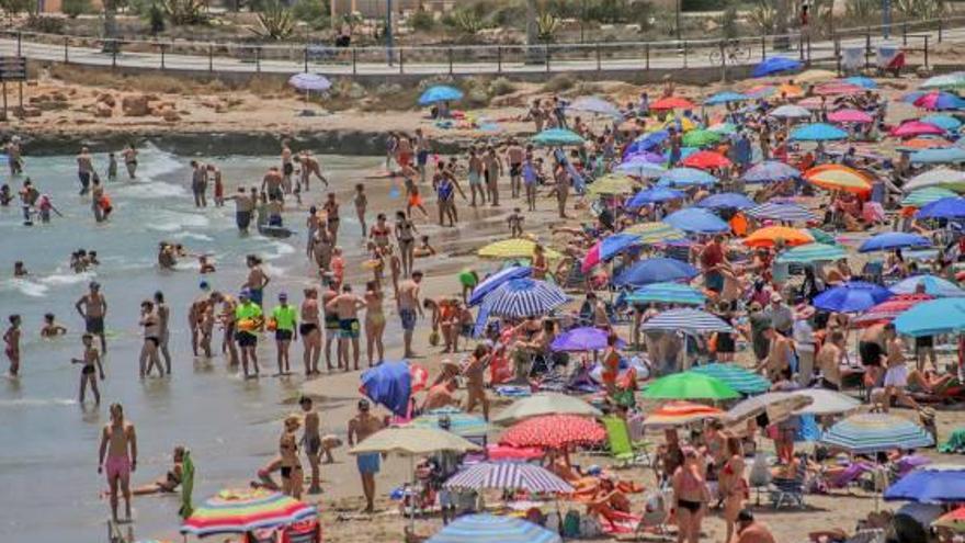 Playa de Cala Bosque en La Zenia (Orihuela Costa), ayer, convertida en un mar de sombrillas.