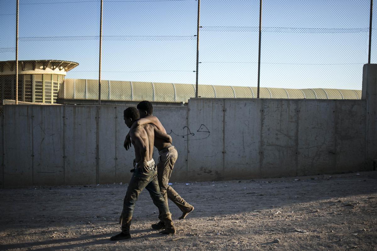 Ein Migrant hilft einem anderen, nachdem er die Zäune zwischen der spanischen autonomen Stadt Melilla in Nordafrika und Marokko überquert hat.
