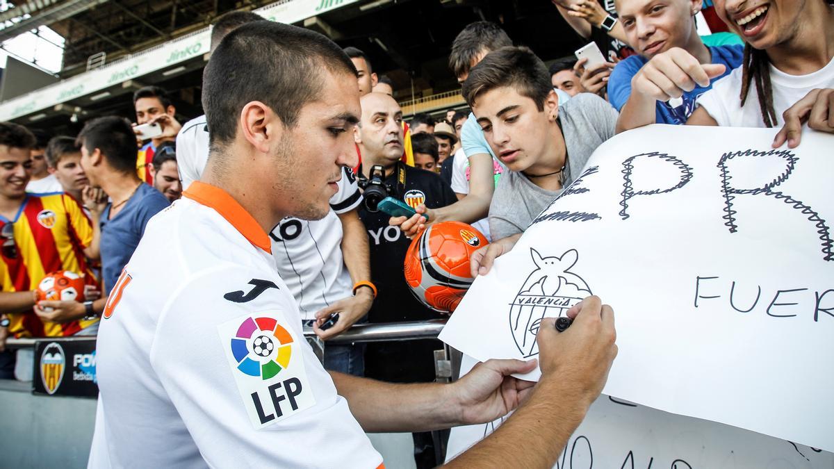 Romeu firma un póster en su presentación con el Valencia en Mestalla en 2013.