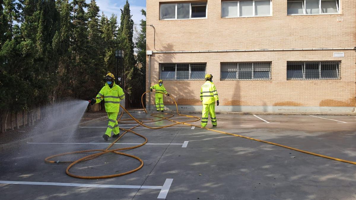 Los  bomberos forestales desinfectando los accesos a un edificio de Crevillent