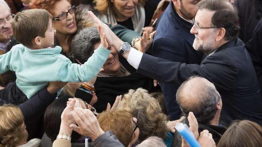 El presidente del Gobierno, Mariano Rajoy, saluda a un niño a su llegada al mitin de Sevilla. // Efe