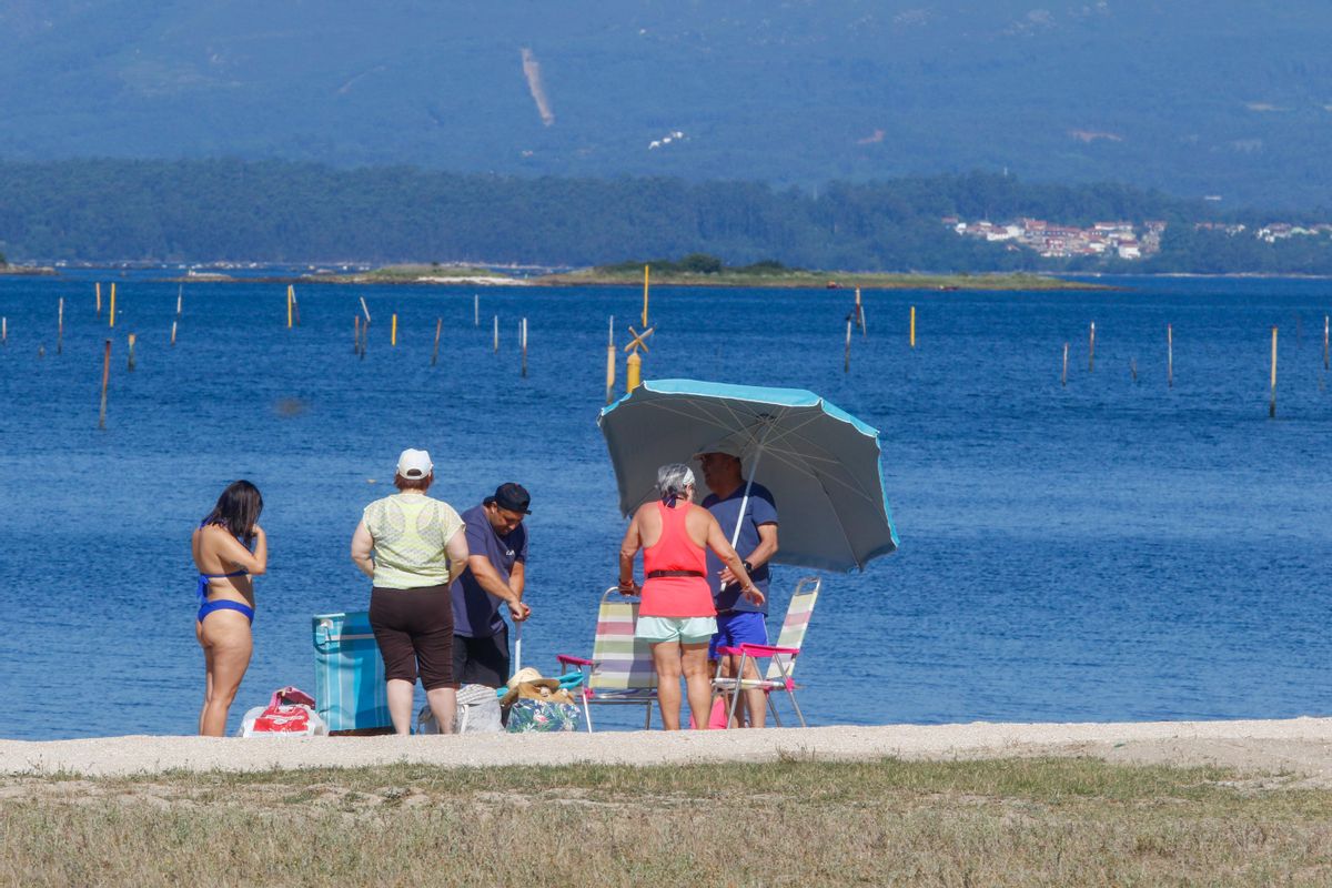 Unos de los primeros bañistas que ayer se instalaron en la playa urbana de Vilagarcía.