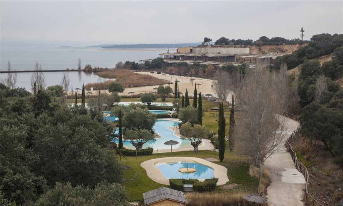Imagen de las piscinas y playa artificial de Marina Isla Valdecañas, con edificaciones a medias al fondo.