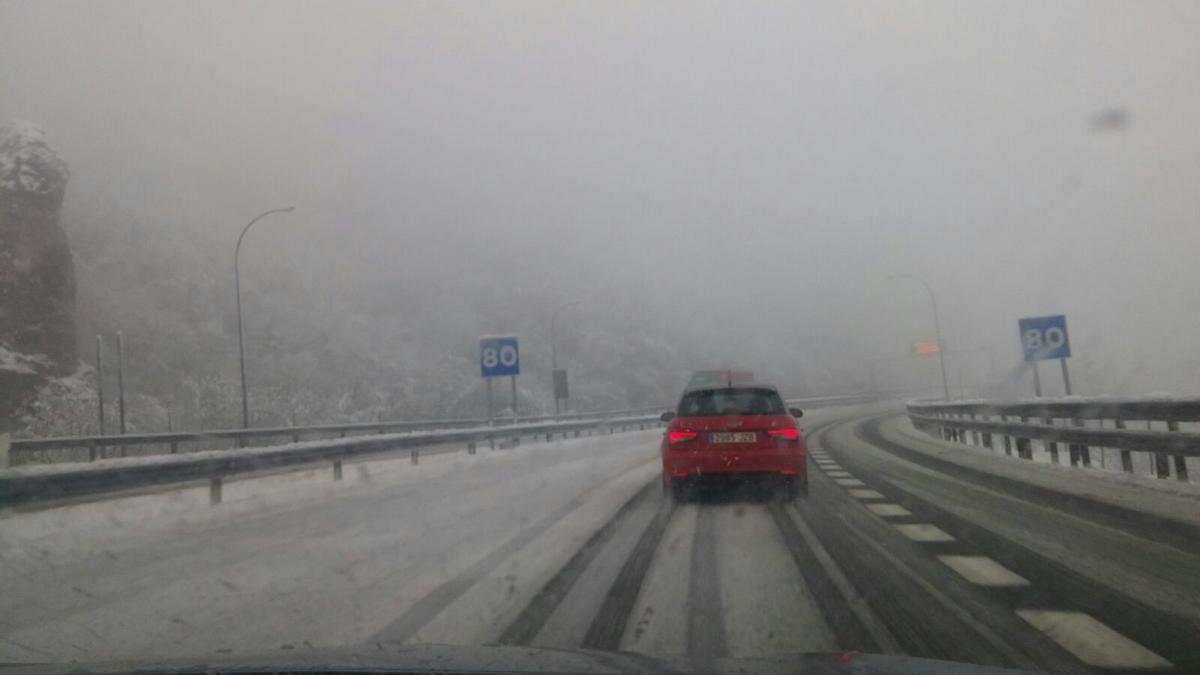 Un coche, por el Huerna, con la autopista nevada este mes de febrero.