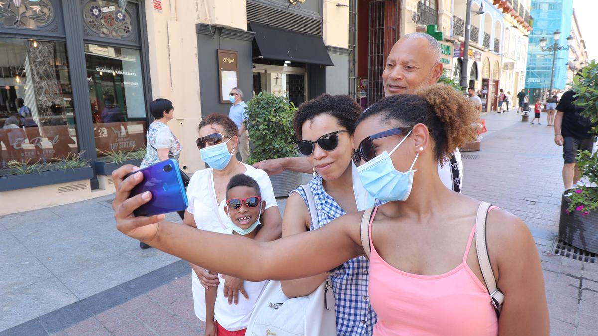 Una familia de turistas se hace una foto en la céntrica calle Alfonso de Zaragoza.