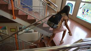 Una niña sube las escaleras de su escuela en Barcelona este curso con el móvil en la mano.