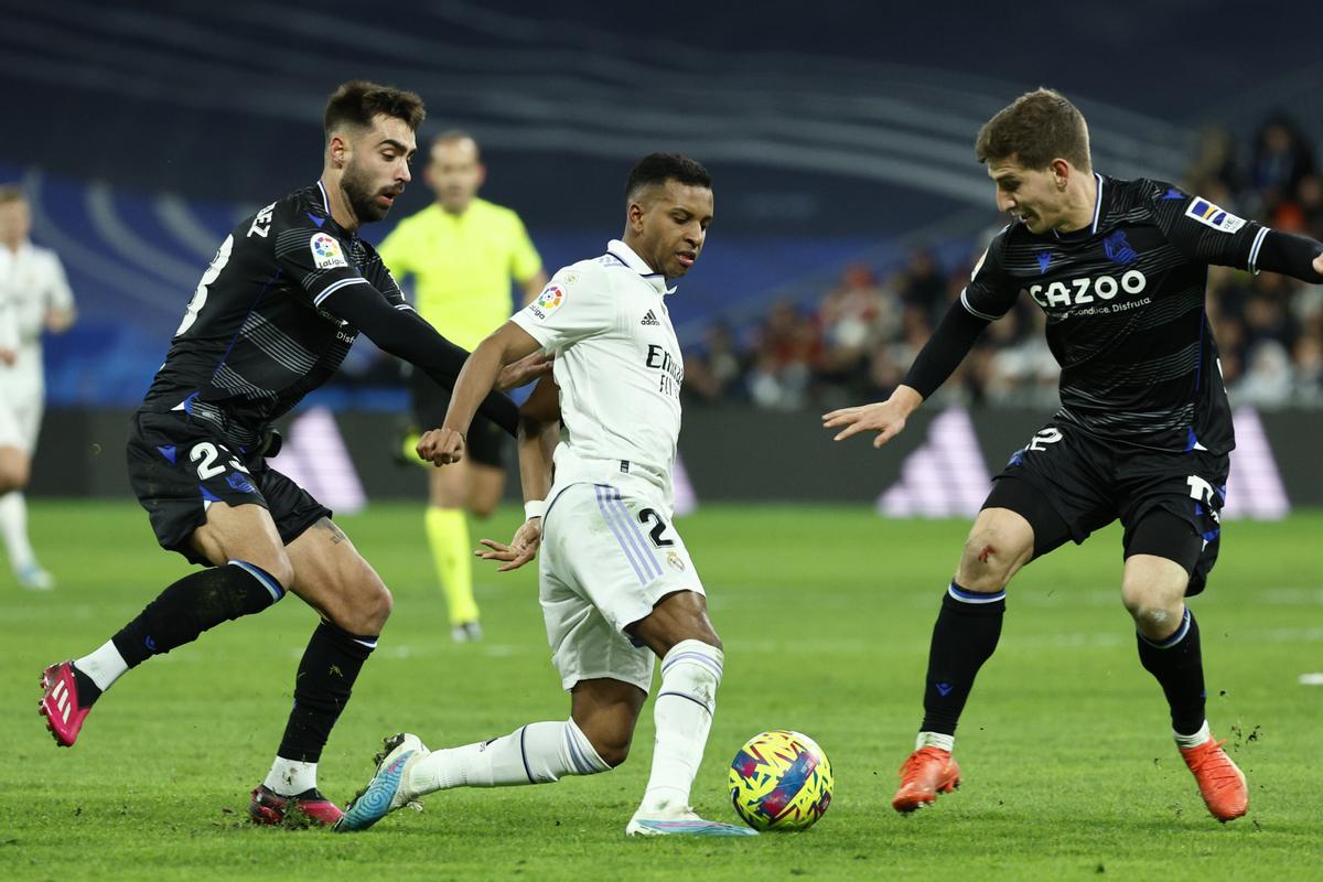 MADRID, 29/01/2023.- El delantero brasileño del Real Madrid, Rodrygo (c), con el balón ante los jugadores de la Real Sociedad, Brais Méndez (i) y Aihen Muñoz, durante el encuentro correspondiente a la jornada 19 de primera división que disputan hoy Domingo en el estadio Santiago Bernabéu, en Madrid. EFE / Rodrigo Jiménez.