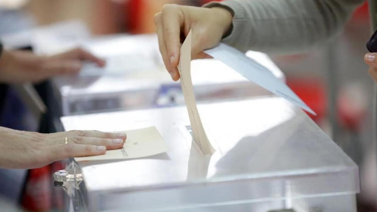 Una persona inserta una papeleta en la urna de votación