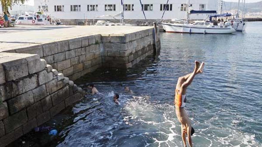 Un grupo de jóvenes bañándose y lanzándose de cabeza al agua en As Avenidas.  // Marta G. Brea