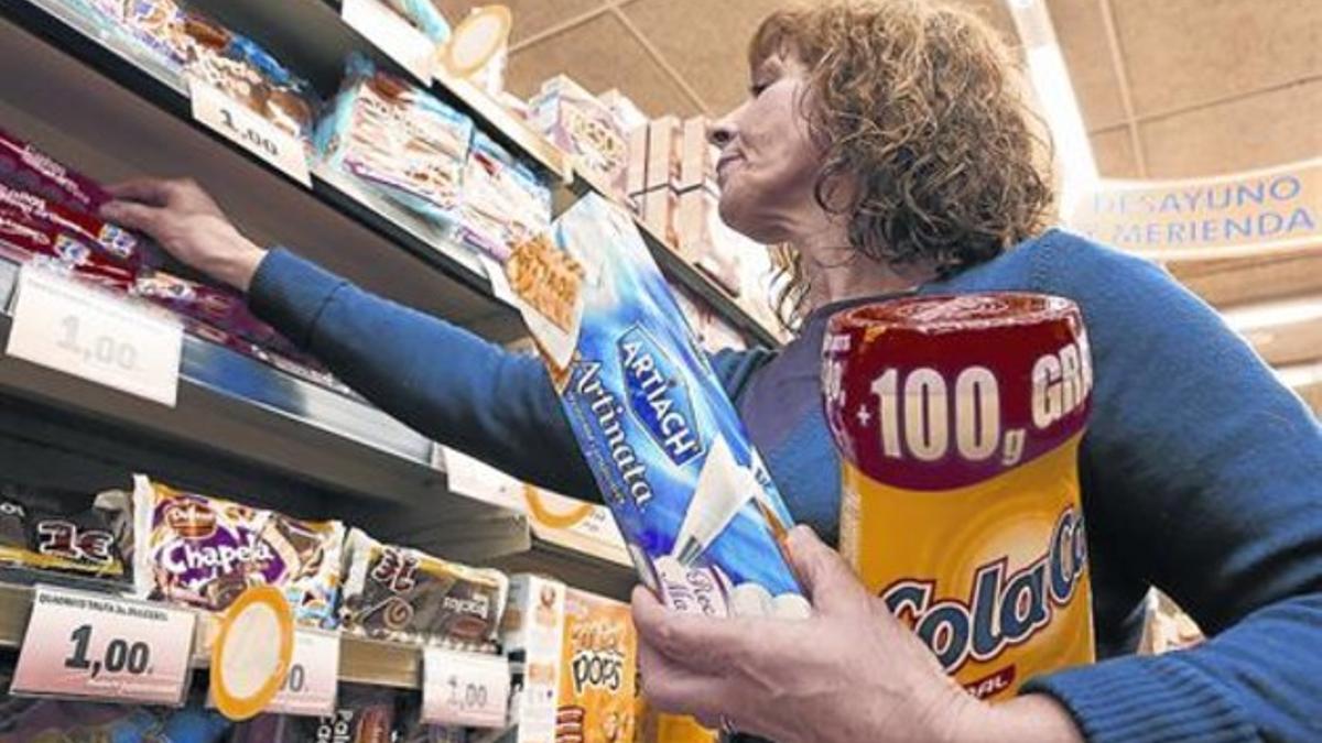Una mujer compra Cola Cao y galletas Artiach, de Nutrexpa, en un supermercado.