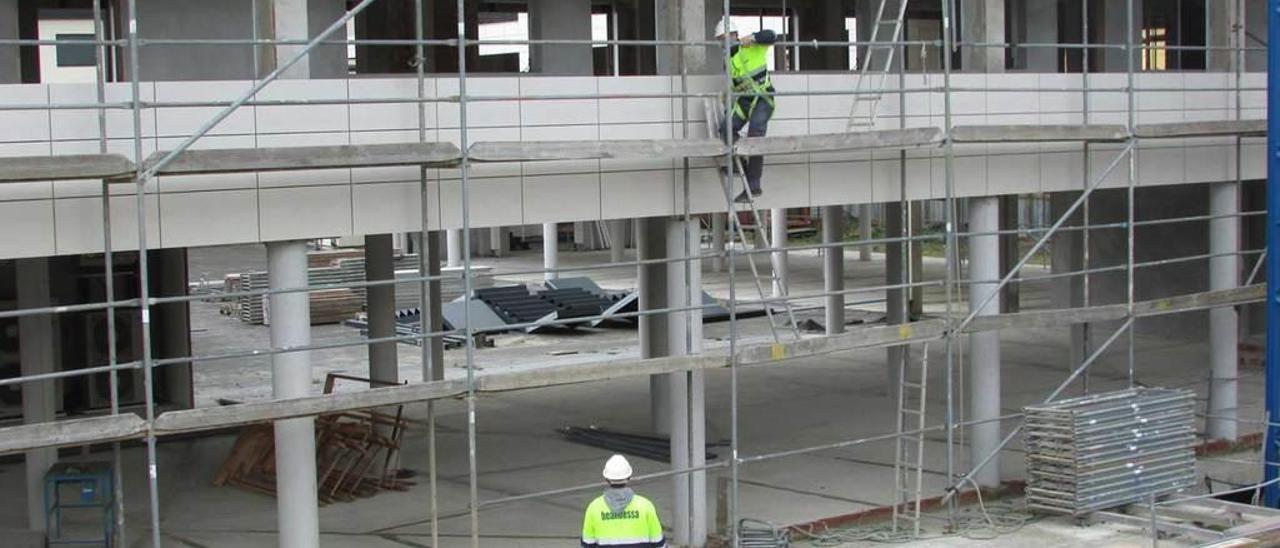 Dos obreros, ayer, retirando el andamiaje en el nuevo edificio del hotel Kaype.