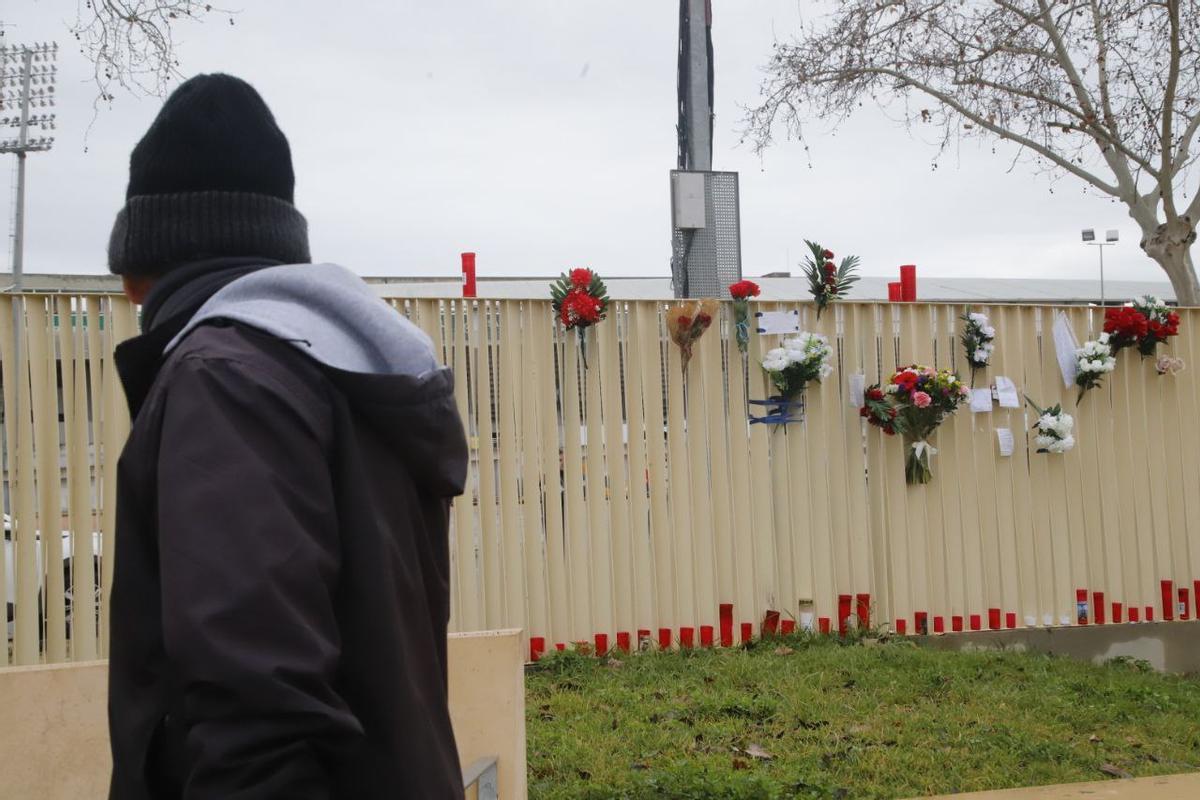Una persona observa las flores, velas y mensajes dejados en El Arenal en homenaje al joven fallecido.