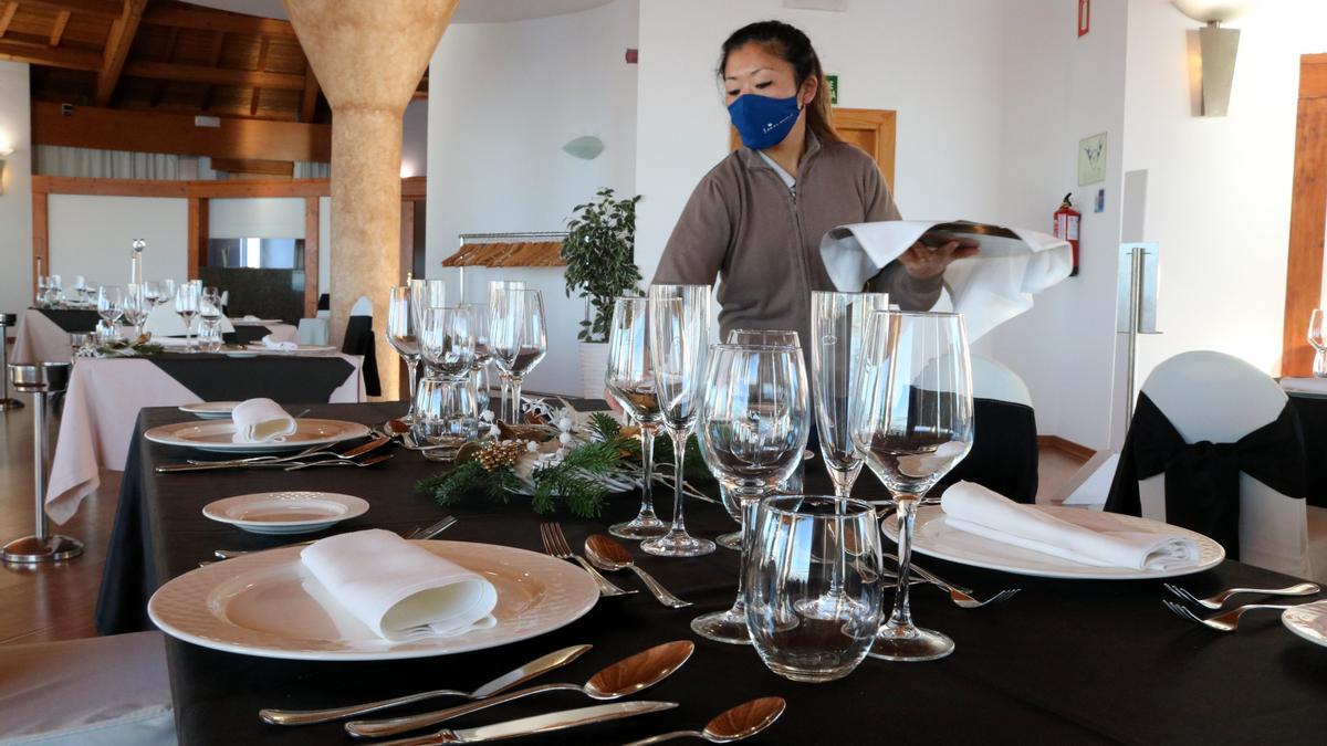 Una cambrera acabant de preparar una taula per la revetlla de Cap d&#039;Any en un hotel