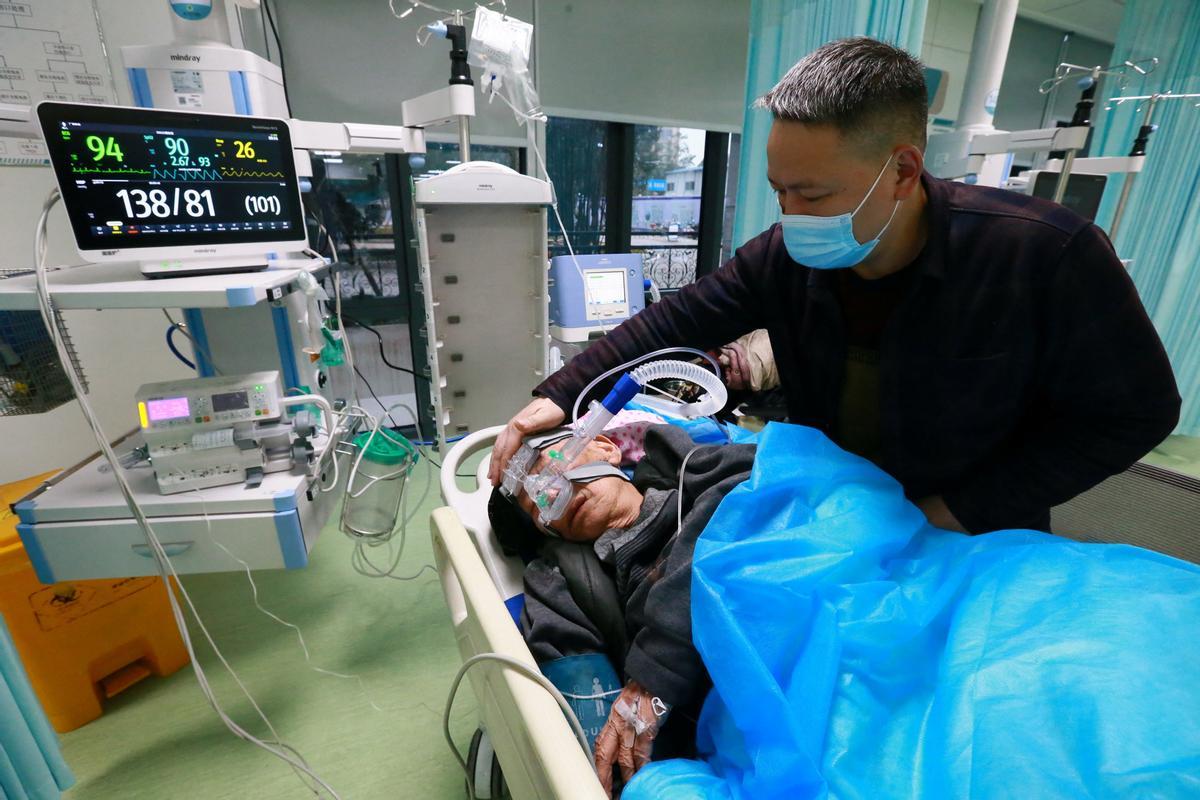 Un familiar atiende a un paciente de la enfermedad por coronavirus (COVID-19) en el departamento de emergencias del Hospital Central de Suining.
