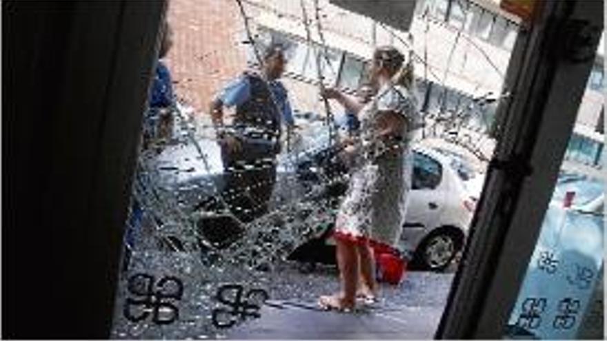 Els Mossos parlen amb la propietària del local, davant d&#039;un vidre trencat.
