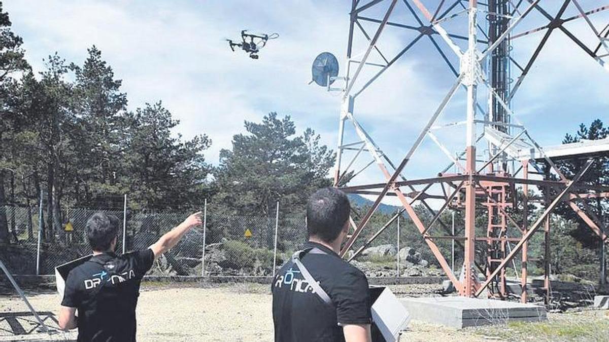 Dos trabajadores utilizan un dron para analizar una torre de telecomunicaciones.