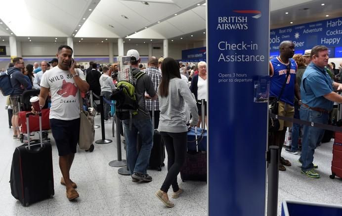 People queue with their luggage for the British ...