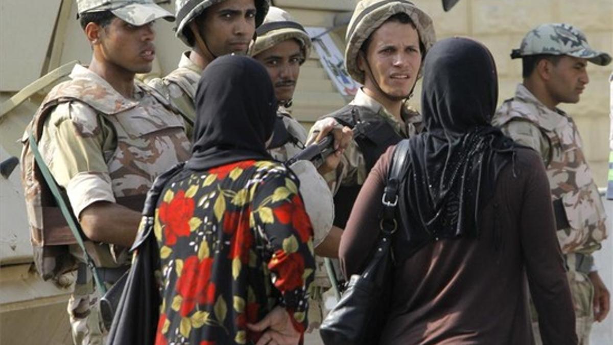 Unas mujeres pasan ayer frente a unos soldados que custodian la prisión de Tora, donde está recluido Hosni Mubarak