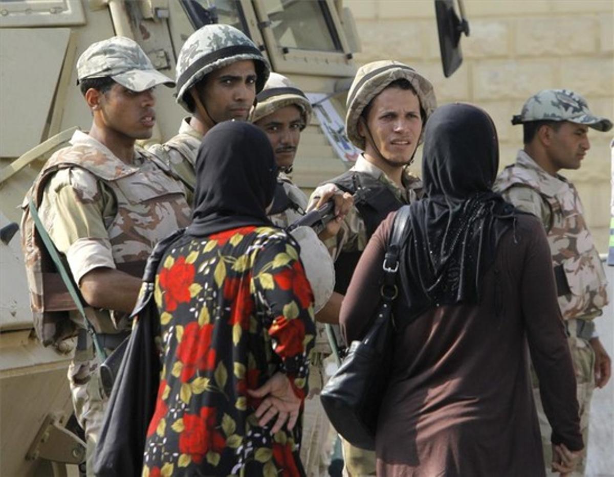 Unes dones passen davant d’uns soldats que custodien la presó de Tora, on està reclòs Hosni Mubàrak, ahir.