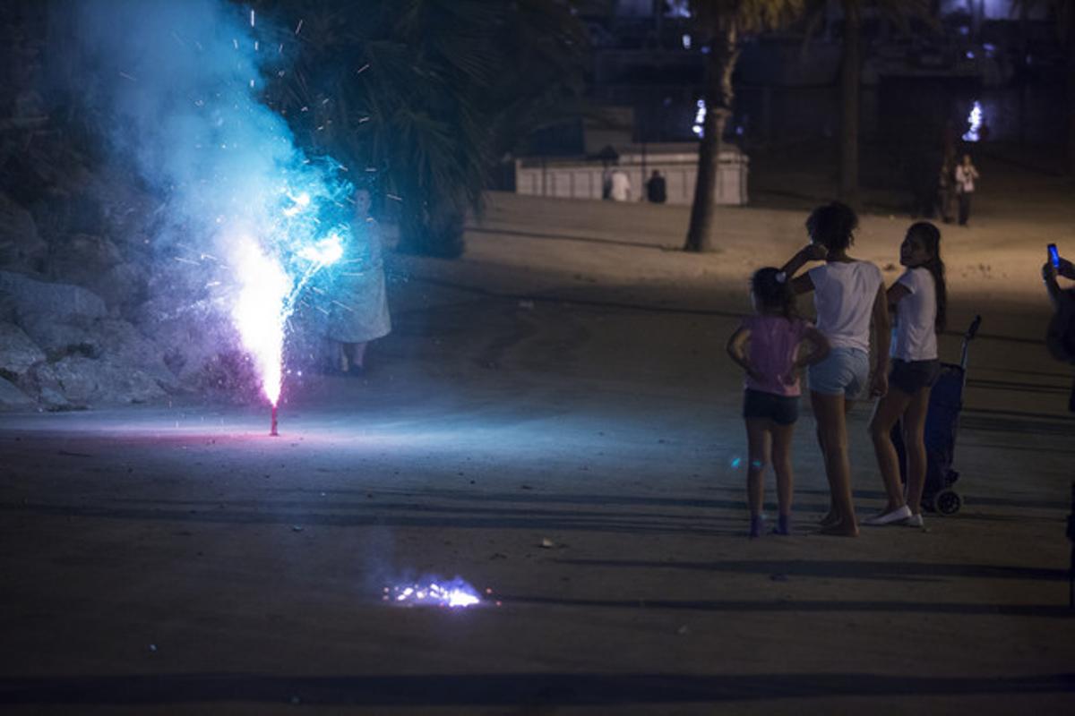 Tres nenes miren una font de colors a la platja de la Barceloneta.