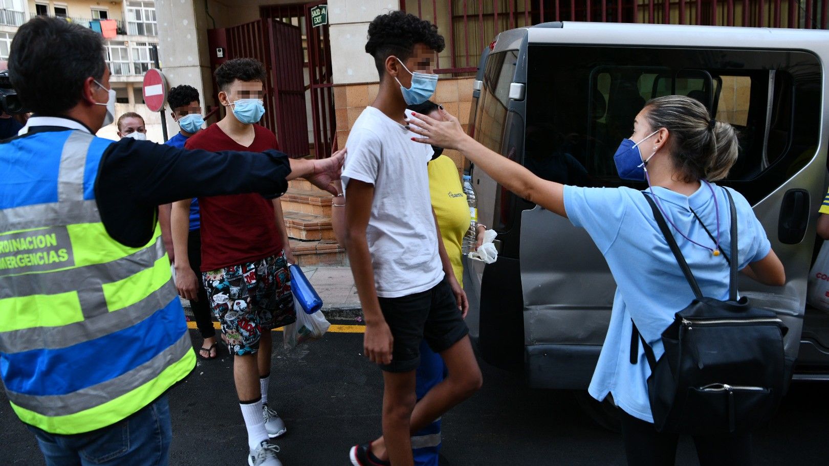 Unos trabajadores de los servicios sociales ayudan a tres de los 15 menores no acompañados marroquís que llegaron a Ceuta de forma masiva el pasado mes de mayo, el pasado día 16