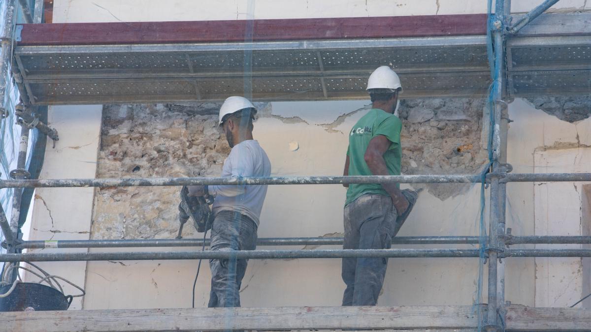 Dos operarios de la construcción en plenos trabajos de reforma de una fachada.